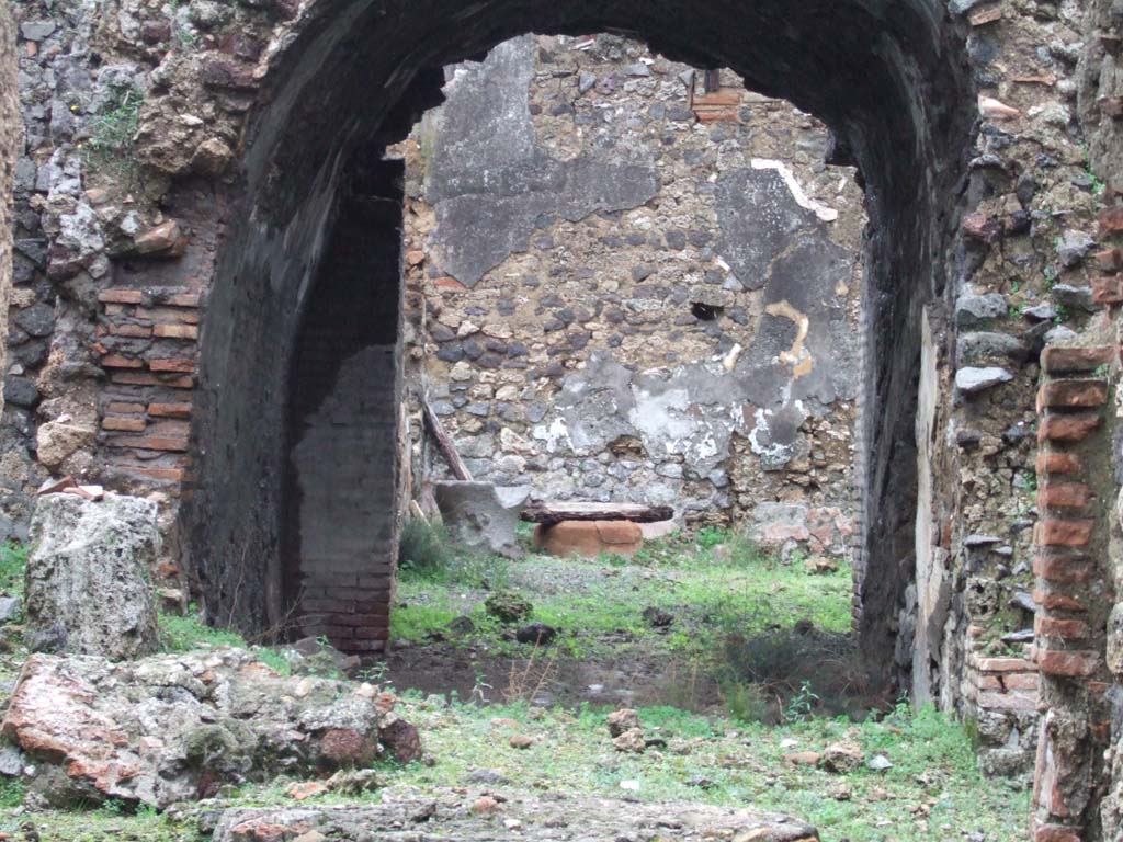 V.2.d Pompeii. December 2005. Looking east through vaulted passageway “g” to the garden.
In the upper north-east corner, just visible through the arch, would have been the niche lararium, shown as “n” on plan. 
