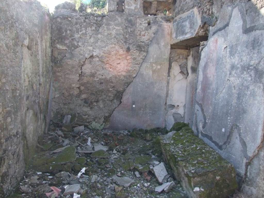 V.4.c Pompeii. March 2009.  Room C, anteroom on north side of entrance corridor. Looking west into anteroom to large triclinium (doorway on right), in north-west corner of atrium.
When discovered, each painted wall of room C was divided into three panels, the centre panel was red and the side panels were black. There were also two horizontal bands, adorned with stylized flowers, which divided the panels from the base of the walls which were painted red, without decoration. In the horizontal bands, decorative objects were suspended from white ribbons, a tambourine in the centre, and two pan-pipes at the sides.
The holes for the beams at the top of the west wall (just visible in photo) showed that the room had been covered by an upper floor. In this room C, on the 1st May 1902, four skeletons with gold and silver coins and other precious objects, were found, described in NdS, 1902, page 276 and 372. See Notizie degli Scavi, 1905, p.131-2.
