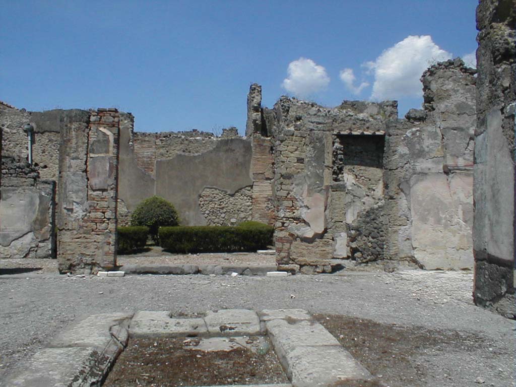 VI.14.12 Pompeii. May 2005. North-east side of atrium, with doorway to garden in the centre.
In the north-east corner is the doorway leading to the winter triclinium, and steps to upper floor. On the right, the east ala can be seen.
