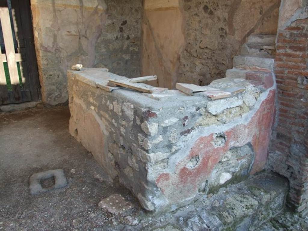 VI.16.33 Pompeii. May 2005. Two-sided masonry counter, and shelving for display. These four small shelves, on the right, were made from masonry and were painted red. According to NdS, a painted figure was seen at the extreme end of the counter, on the left, in its north facing arm. This male figure was 0.57m high, with long yellow robe raised by his erect phallus. The same figure was painted opposite.
