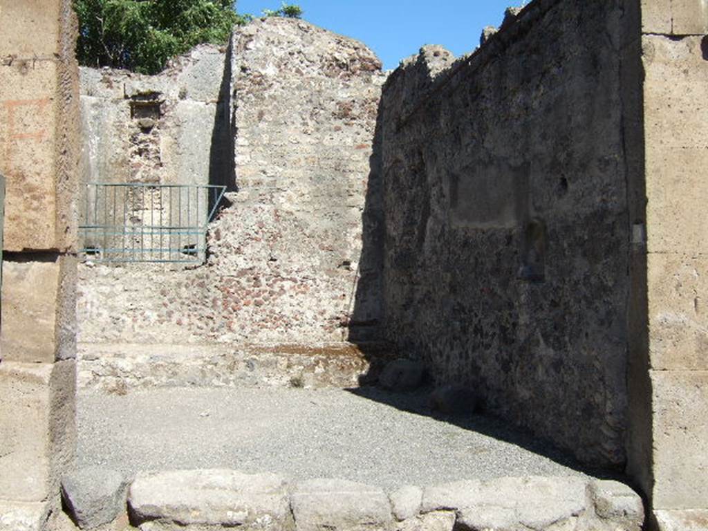 VII.1.49 Pompeii. September 2005. Entrance to workshop L, looking east. At the rear behind the safety railings is the deep well M. The raised strip In front of the well is the site of the treadmill M1 used to raise water.