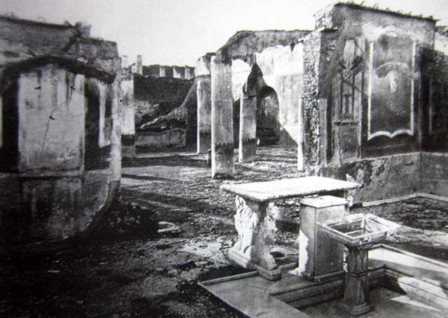 VII.1.25 Pompeii. Old undated 19th century photo. Looking north-west across atrium 24. 
According to Breton, via a prothyrum paved in opus signinum patterned symmetrically with small white stones, we enter the Tuscan atrium; at the centre is a very pretty impluvium of marble at the top of which is a covered square cippus of marble with a lead pipe who poured water into a basin on a small base of marble adorned with large acanthus leaves. The fountain is accompanied by a white marble table with two feet of very fine workmanship, each composed of the anterior part of a chimera and a griffon. On the side top of the table is engraved the number LXXIX and we found a small bronze group representing Hercules armed with his club and a young Phrygian kneeling in front of him.
See Breton, Ernest. 1855. Pompeia, décrite et dessine: Seconde édition . Paris, Baudry, p. 316.

