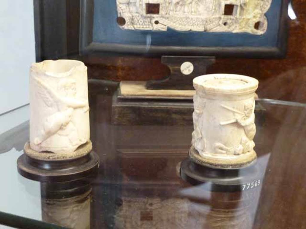 VII.6.28 Pompeii. May 2010. On the right, a small ivory jar with figures in relief, found 29th May 1762.
Now in Naples Archaeological Museum. Inventory number 77569
(See also Sangiorgio 4932; Ceci, tav. VIII, 44).

