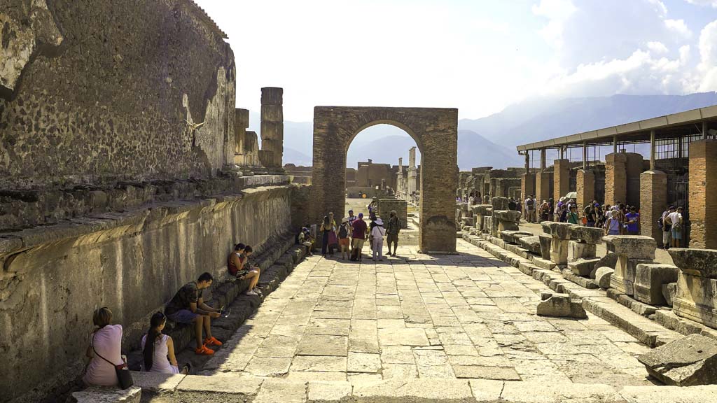 VII.8.1 Pompeii. August 2021. 
Looking south with west wall of Temple of Jupiter, on left, towards Arch of Augustus in north-west corner of Forum. Photo courtesy of Robert Hanson.
