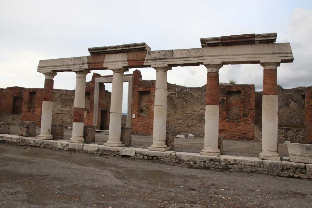 VII.9.1 Pompeii, October 2020. 
Looking east across Forum towards Eumachia’s portico, which formed part of the colonnade of the Forum. Photo courtesy of Klaus Heese.
This has fragments of an inscription on the frieze above. (CIL X, 810, 811). The full Latin inscription, which was also recorded at VII.9.67, was 
EUMACHIA L F SACERD[os] PUBL[ica], NOMINE SUO ET M NUMISTRI FRONTONIS FILI CHACIDICUM, CRYPTAM, PORTICUS CONCORDIAE AUGUSTAE PIETATI SUA PEQUNIA FECIT CADEMQUE DEDICAVIT.
Eumachia, daughter of Lucius, public priestess, in her own name and that of her son, Marcus Numistrius Fronto, built at her own expense the colonnade, corridor and portico in honour of Augustan Concord and Piety and also dedicated them. 
See Cooley, A. and M.G.L., 2004. Pompeii: A Sourcebook. London: Routledge. (p. 100, E42) 
See Mau, A., 1907, translated by Kelsey F. W. Pompeii: Its Life and Art. New York: Macmillan. (p. 111).

