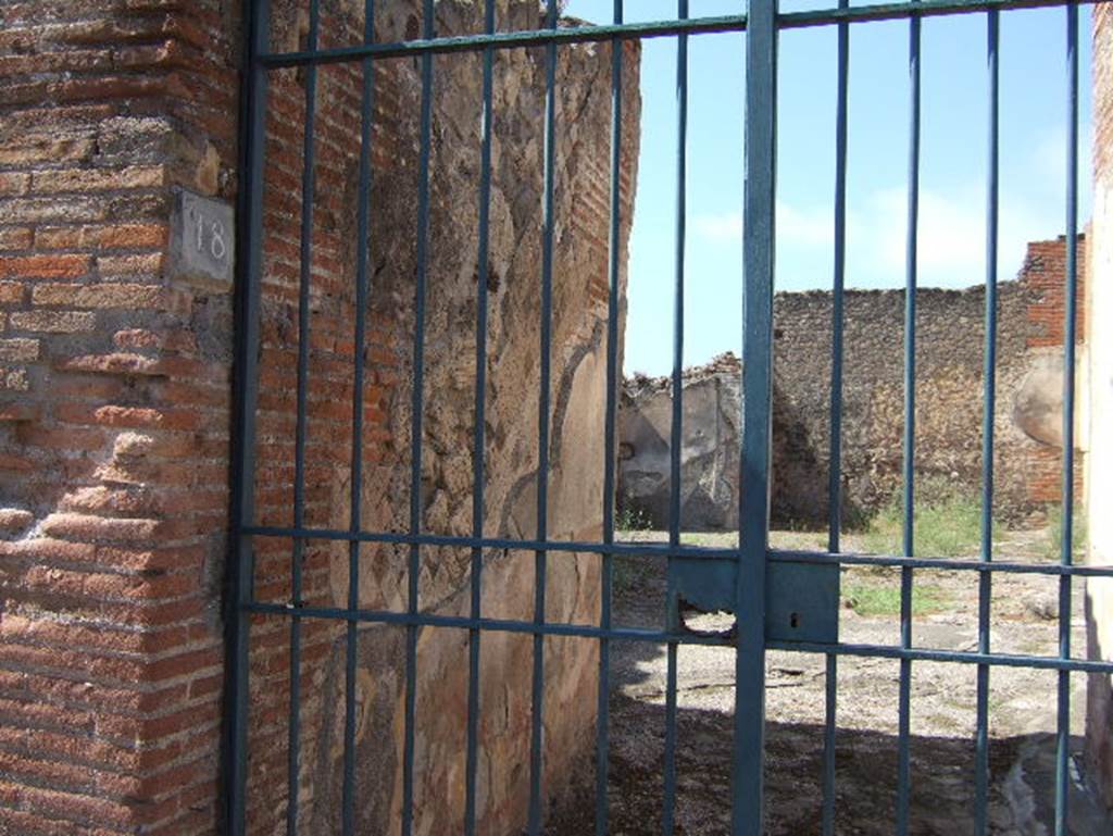 VIII.2.18 Pompeii. September 2005. Doorway and south side of entrance corridor.
According to PPM –
“The walls of the vestibule were in “opus reticulatum” of excellent workmanship, and with brick door-jambs. 
The walls were decorated in the IV Style with a high red zoccolo/plinth/dado painted with panels bordered in a “carpet” design edged with triangles. 
The middle areas of the walls were painted black. The mosaic flooring was of large black tiles/tesserae.”
See Carratelli, G. P., 1990-2003. Pompei: Pitture e Mosaici: Vol. VIII. Roma: Istituto della enciclopedia italiana, (p.115, no.34)
