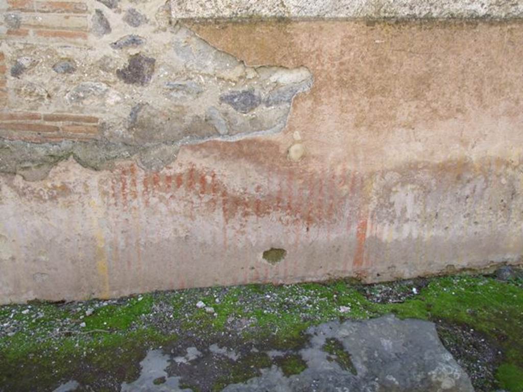 VIII.6.7 Pompeii. March 2009.  Vicolo della Parete Rossa. Remains of painted decoration on outside wall on east side of entrance.
According to PPM, 
The plaster that covered the zoccolo was painted in a false marble with red veins in the central panel and yellow veins in the side ones.
The red vertical veins, painted on the protruding plinth of cocciopesto, are more intense than the yellow ones placed on the sides
(Le venature verticali rosse, dipinte sullo zoccolo sporgente di cocciopesto, sono piu intense di quelle gialle poste ai lati
L’intonaco che copre la parete in opera incerta con cantonale in laterizi, era nello zoccolo a falsi marmi con venature rosse nel pannello centrale e venature gialle in quelli laterali.)
See Carratelli, G. P., 1990-2003. Pompei: Pitture e Mosaici, VIII. Roma: Istituto della enciclopedia italiana, (p.684, and figs. 47 and 48, on p.686).

