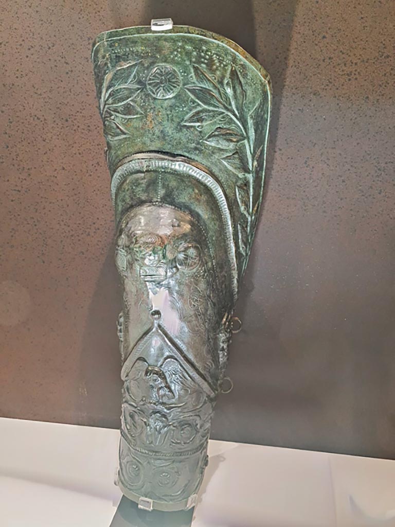 VIII.7.16 Pompeii. Photo taken May 2021, in Naples Archaeological Museum, inv. 5668.
Bronze greave depicting laurel branches, Bacchic masks, heads of Pan and an eagle clasping a hare.
Found 30th December 1766.
Photo courtesy of Giuseppe Ciaramella.

