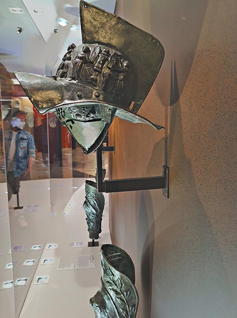 VIII.7.16 Pompeii. Photo taken May 2021, in Naples Archaeological Museum, inv. 5674.
Murmillo gladiator’s helmet, with personification of Rome, Barbarian captives, trophies and Victories, in display case. 
Photo courtesy of Giuseppe Ciaramella.


