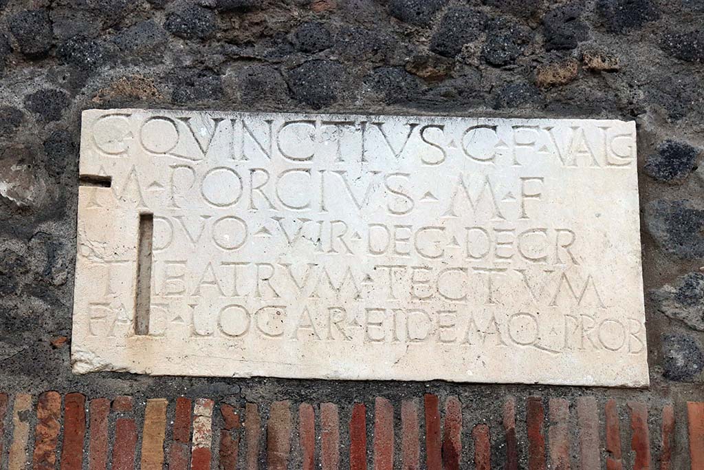 VIII.7.21 Pompeii. September 2017. Identical dedication plaque above entrance VIII.7.19 on Via Stabiana. Photo courtesy of Klaus Heese.
C QVINCTIVS C F VALG
M PORCIVS M F
DVOVIR DEC DECR
THEATRVM TECTVM
FAC LOCA R EIDEMQ PROB

C(aius) Quinctius C(ai) f(ilius) Valg(us) 
M(arcus) Porcius M(arci) f(ilius)
duovir(i) dec(urionum) decr(eto)
theatrum tectum 
fac(iundum) locar(unt) eidemq(ue) prob(arunt)          [CIL X 844a]

According to Mau, the names of the builders of the Small Theatre are known from an inscription found in the building.
C. Quinctius C. f. Valg[us], M. Porcius M. f. duovir[i] dec[urionum] decr[eto] theatrum tectum fac[iundum] locar[unt] eidemq[ue] prob[arunt]
“Gaius Quinctius Valgus the son of Gaius, and Marcus Porcius the son of Marcus, duumvirs, in accordance with a decree of the city council let the contract for building the covered theatre and approved the work”.
See Mau, A., 1907, translated by Kelsey F. W. Pompeii: Its Life and Art. New York: Macmillan, (p.153).
