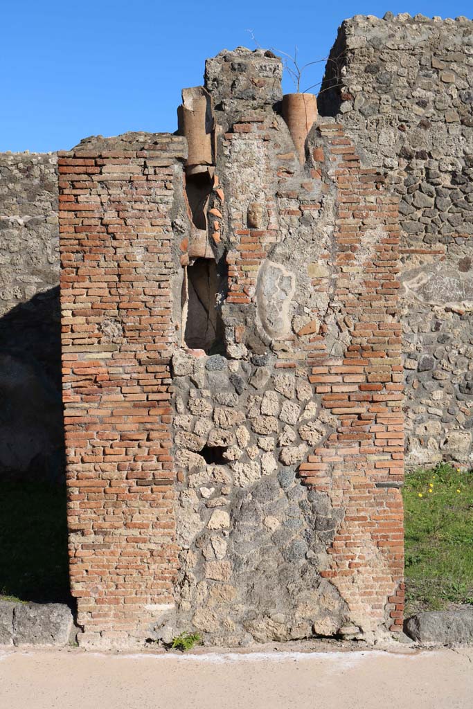 IX.2.2, on left, and IX.2.3, on right. December 2018. 
Central pilaster with downpipe. In the centre of the pilaster is a small terracotta face.
Photo courtesy of Aude Durand.

