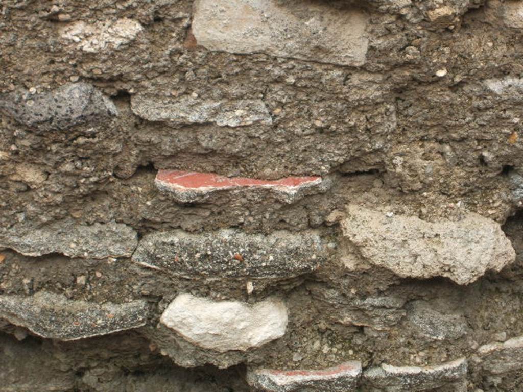 IX.2.23 Pompeii.  May 2005.  Original plaster used to build/repair wall

