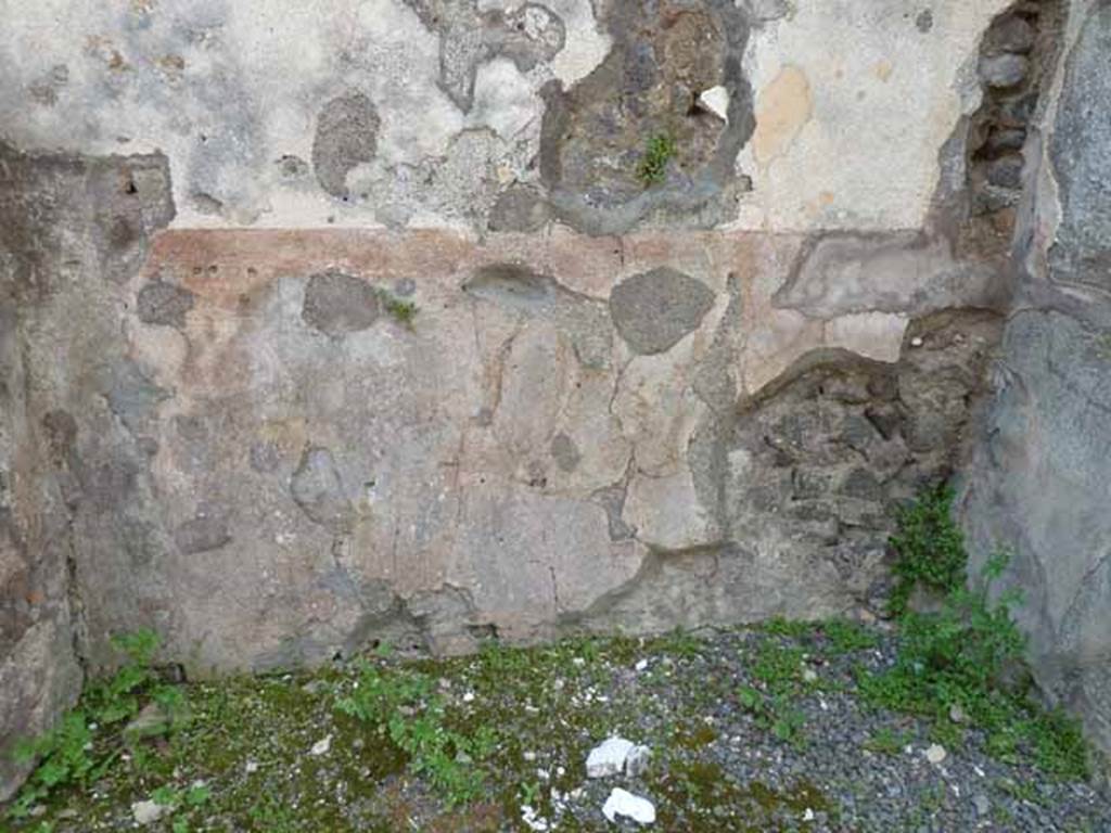 IX.8.2 Pompeii. May 2010. Remains of painted plaster on base of west wall of front room of shop.