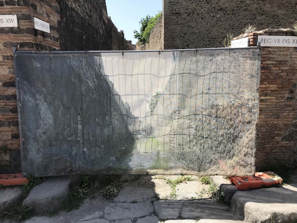 Vicolo degli Scheletri between VII.14 and VII.11. April 2019. 
Looking west from Vicolo del Lupanare towards display screen at junction of roads. Photo courtesy of Rick Bauer.  

