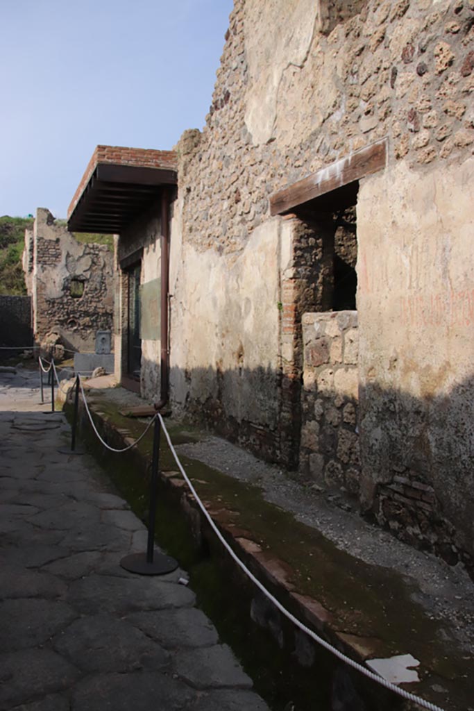 Vicolo dei Balconi, Pompeii. October 2022. 
Looking north to Thermopolium of Nereid (doorway B1) with reconstructed balcony at junction with Vicolo delle Nozze d’Argento. 
In the centre is another house entrance, we number as B2, with a blocked entrance. Photo courtesy of Klaus Heese.

