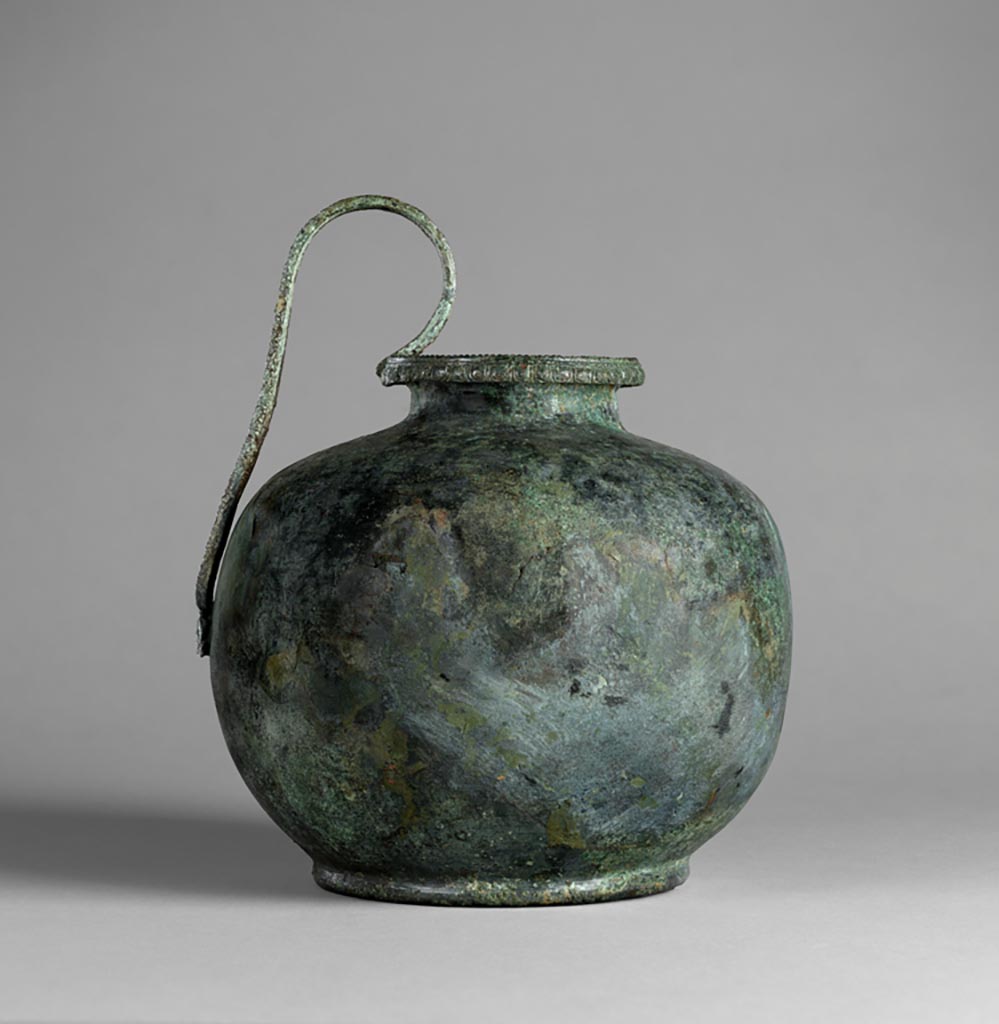 Villa in Boscoreale. Bronze oinochoe. The body of this squat jug is undecorated. 5th century B.C.
Around the outer face of the mouth runs a tongue-and-dart motif, and on the lip, a beaded pattern. 
The edges of the high, arched strap handle are also articulated. 
At the base of the handle is an applique in the shape of volutes (?).
Digital image courtesy of the Getty's Open Content Program. Now in the Getty Museum, inventory number 72.AC.145.
Gorecki proposed that this comes from the Villa of N. Popidius Florus at Boscoreale (excavated in 1906), but that it entered the market prior to the publication of excavations in 1921. This history and the identification of the objects as a group have not been verified by the Getty. Gorecki also observes that three of the items in the group date to a much earlier period (72.AC.136, .137 and .145), suggesting that they might have been added in modern times. [Feb 2022].
See Gorecki J., 1993. Metallgefäße und -objekte aus der Villa des N. Popidius Florus (Boscoreale) im J. Paul Getty Museum, Malibu, Kalifornien in Bronces Y Religión Romana: Actas Del XI Congreso Internacional de Bronces 1990. Madrid: pp. 229-246.
