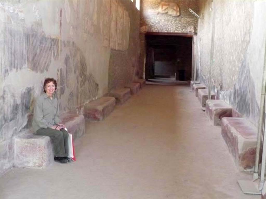 Oplontis, May 2011. Corridor 46, looking west. The benches in the long corridor may have been used as seats, as demonstrated by a willing tourist, but the current guidebook says that they may have been used as supporting surfaces for the working or storage of agricultural products. Photo courtesy of Buzz Ferebee.

