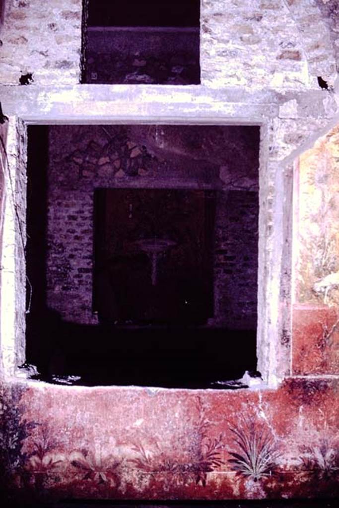 Oplontis, 1976. According to Wilhelmina, this is a window from room 68, a small courtyard-garden where they excavated and found some root-cavities, looking south through the window across room 65, and through another window into room 61.  Photo by Stanley A. Jashemski.   
Source: The Wilhelmina and Stanley A. Jashemski archive in the University of Maryland Library, Special Collections (See collection page) and made available under the Creative Commons Attribution-Non Commercial License v.4. See Licence and use details. J76f0412
According to Wilhelmina, “Stanley took many pictures of the garden paintings on the walls of this garden, also of the view from this garden through the adjacent room to the unique little raised garden with garden paintings beyond.”
