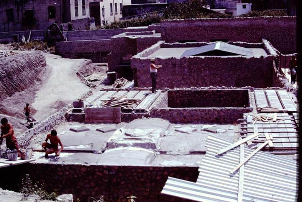 Oplontis, 1977. Reconstruction of the villa, looking south. The two figures on the left are on the roof of room 74. The square hole in the roof is for  room 70, a small raised courtyard garden.  Photo by Stanley A. Jashemski.   
Source: The Wilhelmina and Stanley A. Jashemski archive in the University of Maryland Library, Special Collections (See collection page) and made available under the Creative Commons Attribution-Non Commercial License v.4. See Licence and use details. J77f0119
