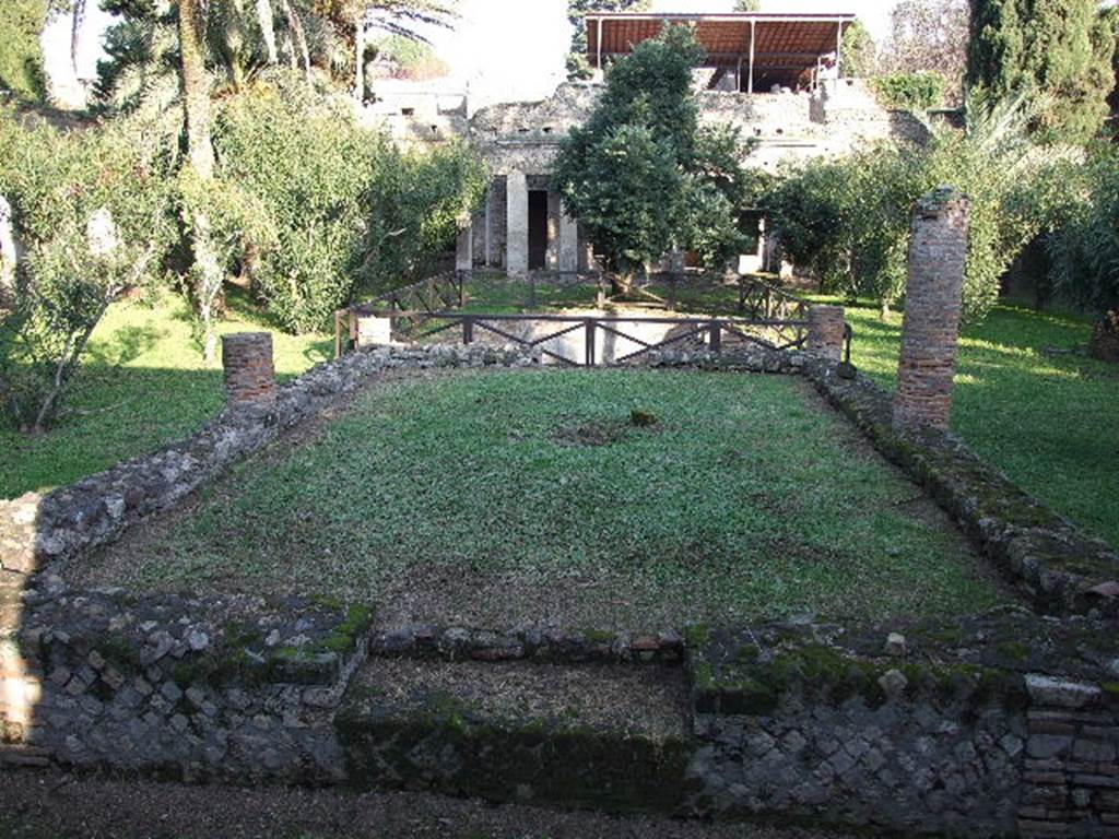 HGW24 Pompeii. December 2006. Looking east over garden across pergola supported by six columns.
According to Jashemski, at the rear of the pool was a raised dining area, shaded by a large vine-covered pergola.
See Jashemski, W. F., 1993. The Gardens of Pompeii, Volume II: Appendices. New York: Caratzas. (p.281).
The area of La Vega’s no. 13 (between top two columns, on right), no.14 on left of photo, (in north-west corner of pergola) and no.79 (approximately near the palm-tree, on the left) can all be seen.  
